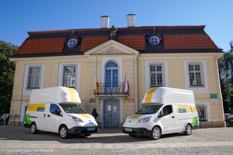 Dwa auta elektryczne stoją przed budynkiem Urzędu Stanu Cywilnego w Białymstoku