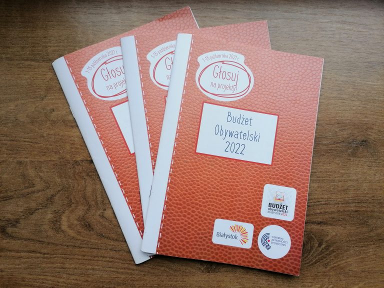 Na stole leżą trzy broszury informacyjne dotyczące budżetu obywatelskiego