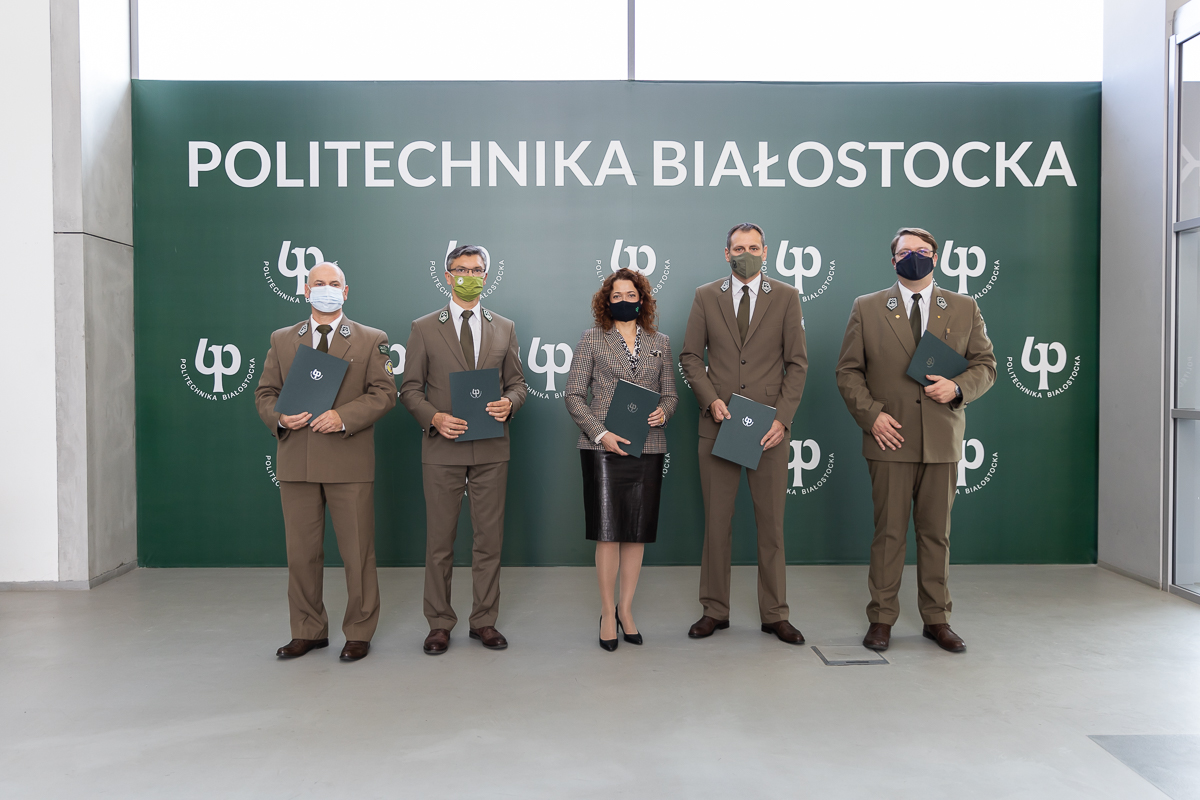 Czterech mężczyzn i kobieta stoją trzymając w dłoniach teczki z umową