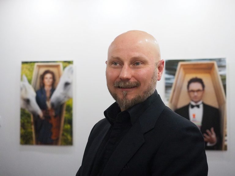 Mężczyzna w galerii, na ścianie wiszą jego prace