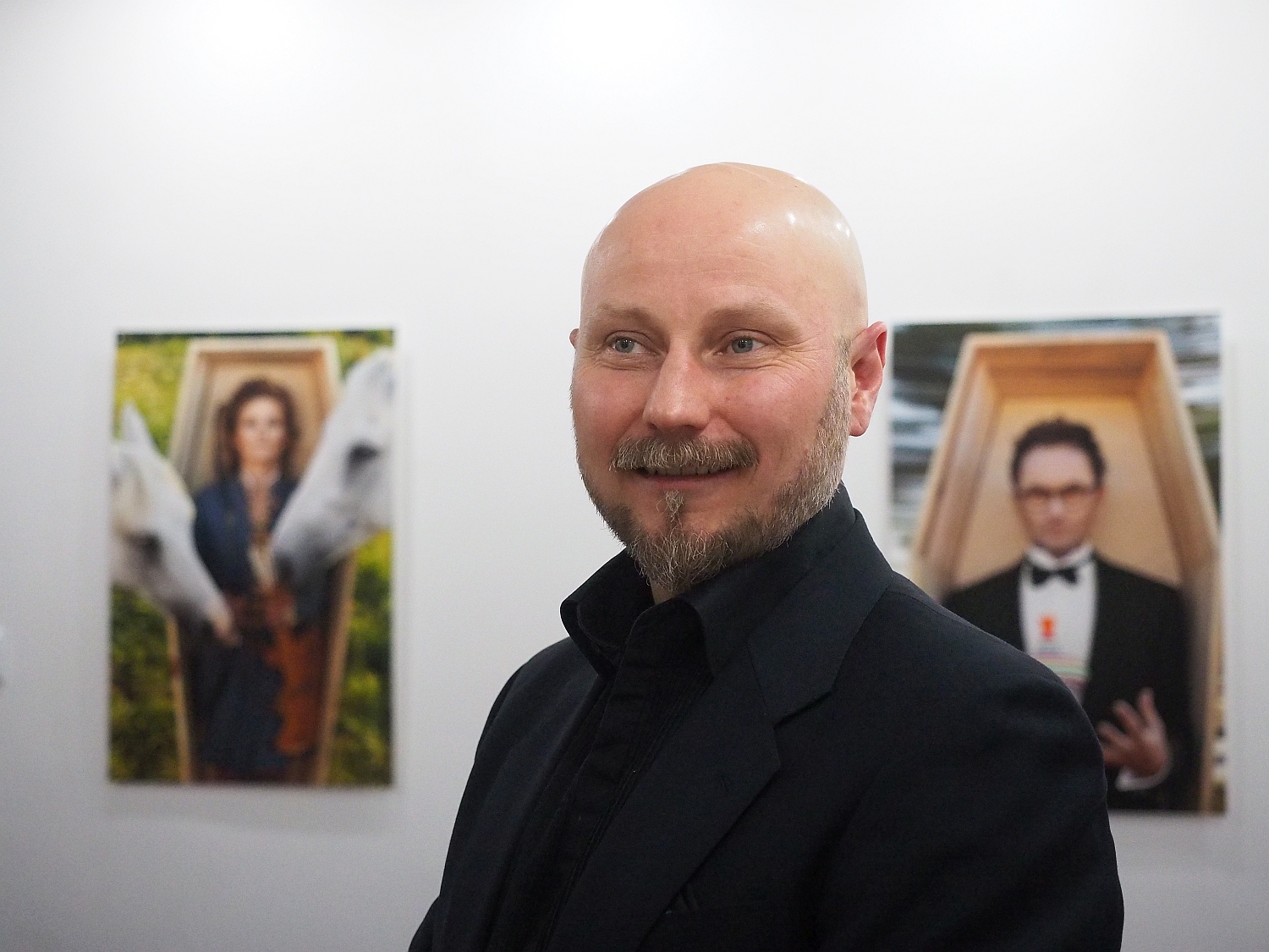 Mężczyzna w galerii, na ścianie wiszą jego prace