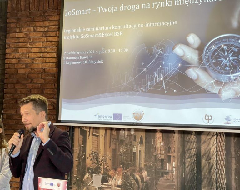 Na rzutniku wyświetlane są informacje na temat program GoSmart. Z lewej strony stoi mężczyzna,, który mówi przez mikrofon