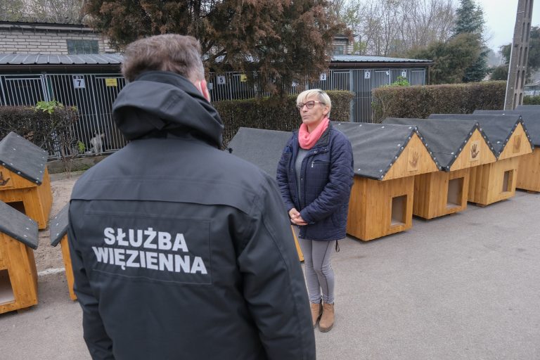 Przedstawiciel Służby Więziennej przekazuje odnowione przez więźniów budy dla psów