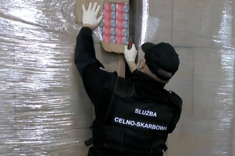 Funkcjonariusz KAS wyjmuje papierosy z kartonu