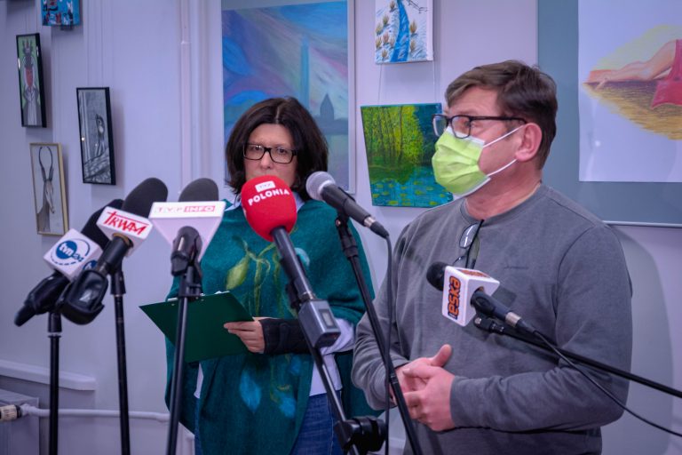 Dwie osoby stoją przy mikrofonach dziennikarzy