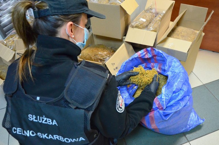 Funkcjonariusz KAS przy pudełkach z nielegalnym tytoniem