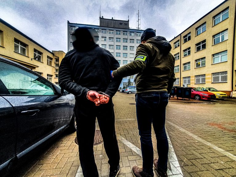 Policjant trzyma pod rękę mężczyznę podejrzanego o kradzież