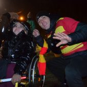 Niepełnosprawni kibice czekają na racowisko i odpalenie rac przy stadionie miejskim w Białymstoku. Kobieta na wózku inwalidzkim i kibic w koszulce w klubowych barwach Jagielloni