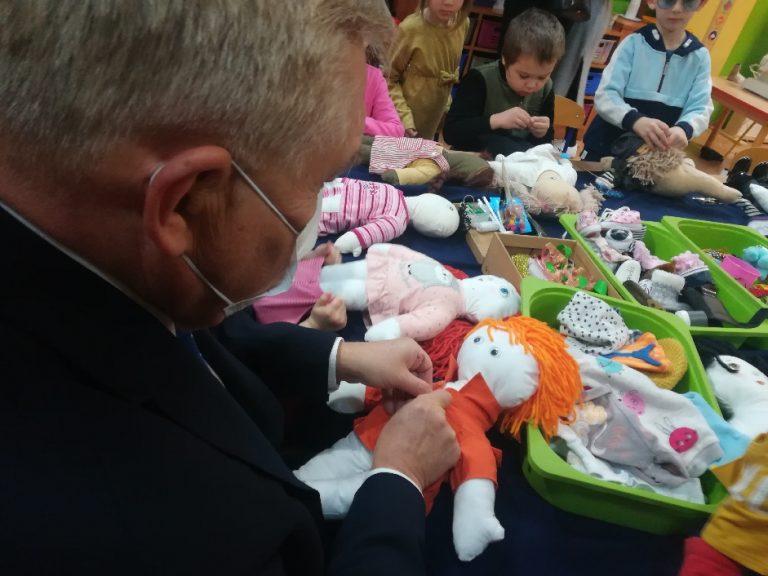mężczyzna tworzy szmacianą lalkę przy stoliku w przedszkolu