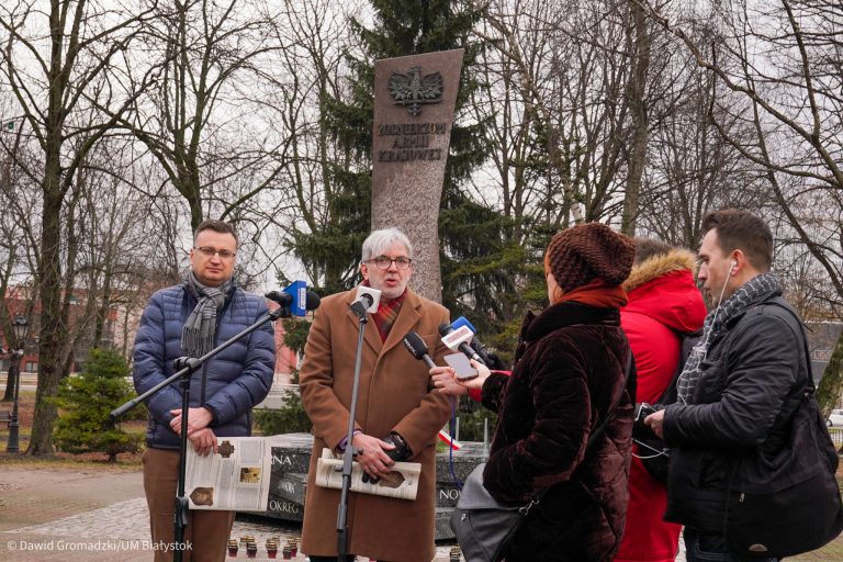 Konferencja prasowa, grupka ludzi stoi przy Pomniku AK