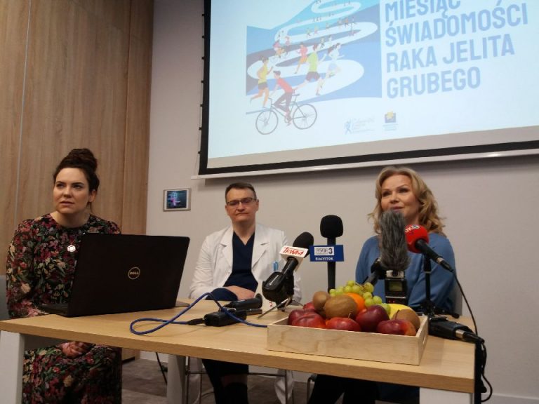 Przy stole siedzą trzy osoby podczas konferencji prasowej