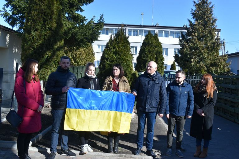 ludzie stoją z flagą ukraińską