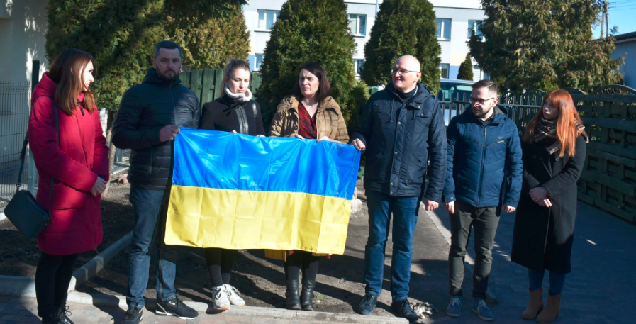 ludzie stoją z flagą ukraińską