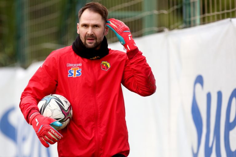 Piłkarz na boisku trzyma pod pachą piłkę