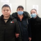 Chłopiec i dwie kobiety - uchodźcy z Ukrainy stoją w punkcie darów na stadionie