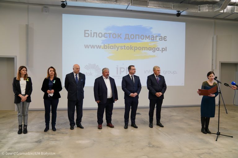 Ludzie stoją na tle wyświetlonej strony internetowej