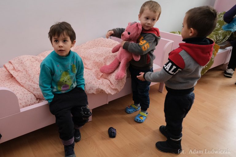 Małe dzieci swotą przy łóżku w pokoju