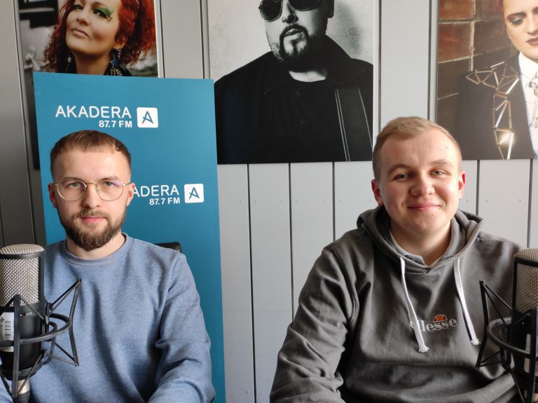 Dwaj młodzi mężczyźni siedzą za stołem w radiowym studio