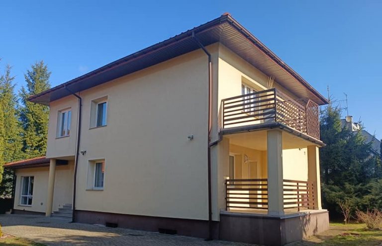 Piętrowy, murowany dom pomalowany na biszkoptowy kolor