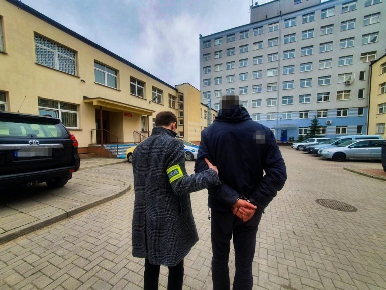 Policjant prowadzi skutego kajdankami mężczyznę