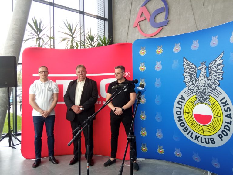 Trzej męźczyźni stoją przed mikrofonami na konferencji prasowej