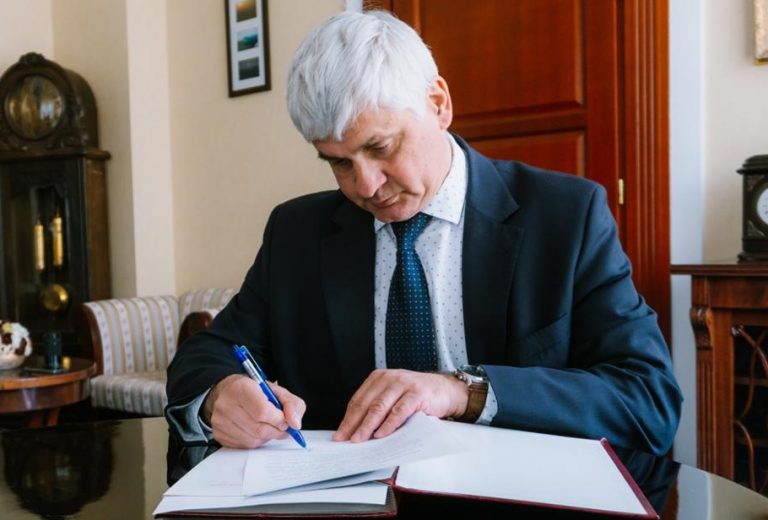 Siwy mężczyzna podpisuje dokumenty przy biurku