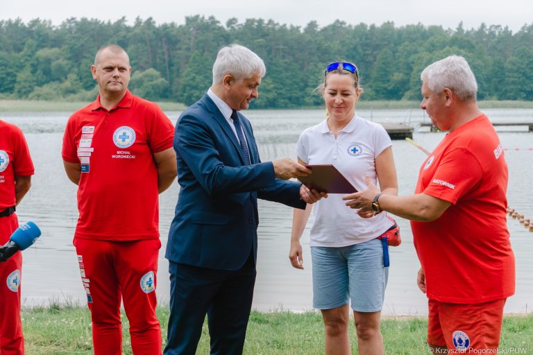 Kilka osób stoi nad wodą