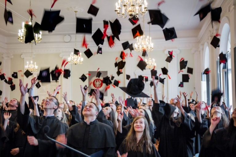 grupa studenów podrzuca do góry birety
