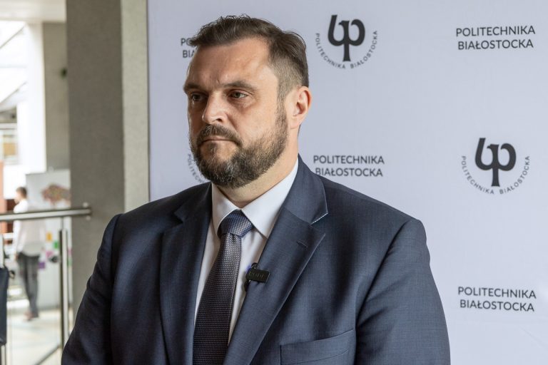 mężczyzna na tle baneru Politechniki Białostockiej
