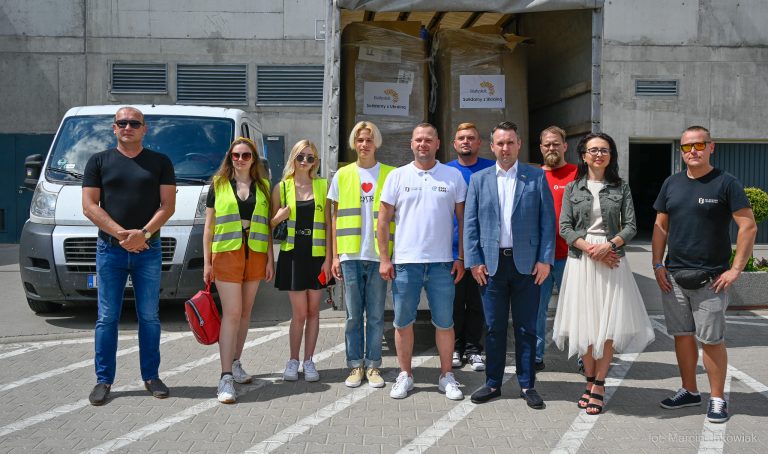 Ludzie stoją na tle załadowanego darami samochodu