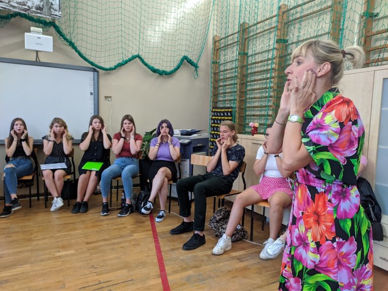 Grupa młodych ludzi w sali wykonuje ćwiczenia dykcyjne
