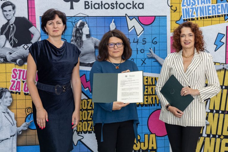 Trzy kobiety elegancko ubrane, dwie z nich trzymają teczki z dokumentem