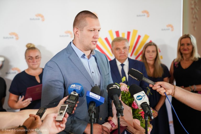 Wysoki mężczyzna mówi do mikrofonu dziennikarzy