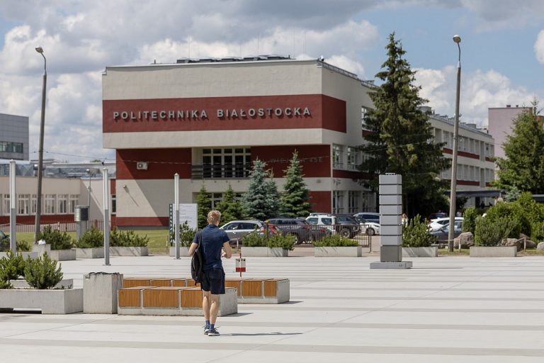 Budynek politechniki białostockiej, na placu przed budynkiem idzie młody mężczyzna