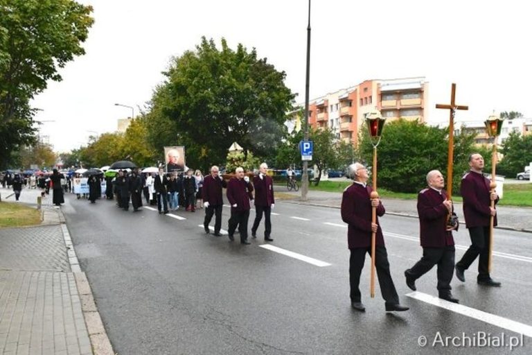 uczestnicy procesji niosący krzyż i portret błogosławionego księdza Sopoćki