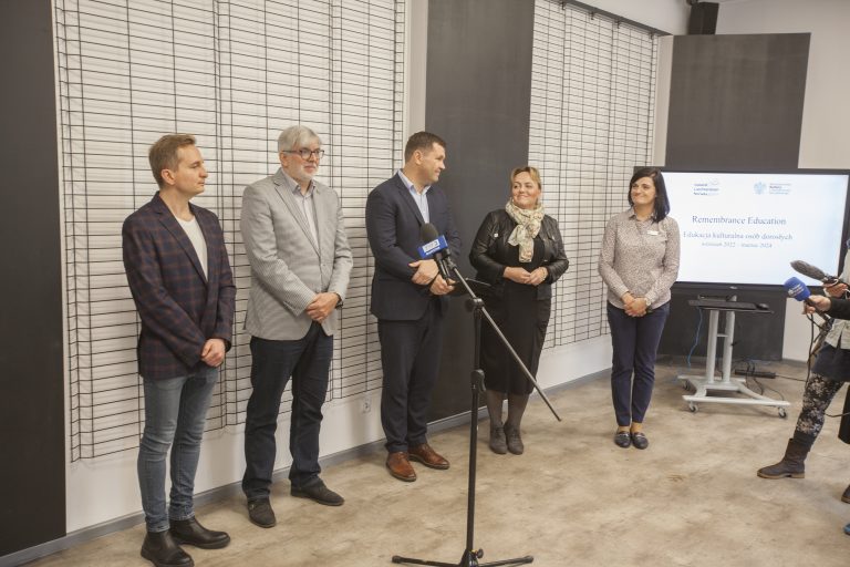 Pięc osób stoi przed mikrofonami podczas konferencji prasowej