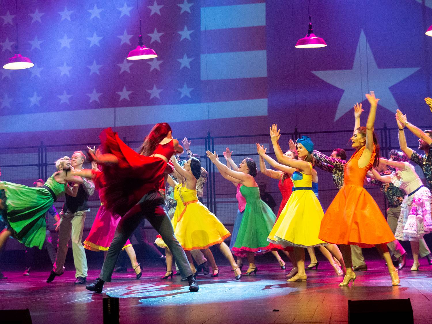 Tancerze ubrani w kolorowe ubrania tańczą na scenie