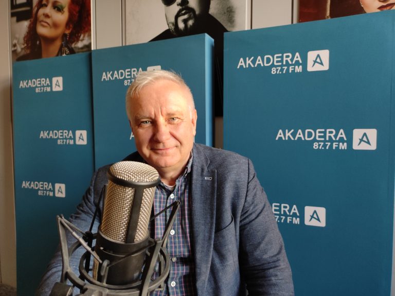 Siwy meżczyzna siedzi w studio radiowym przed mikrofonem