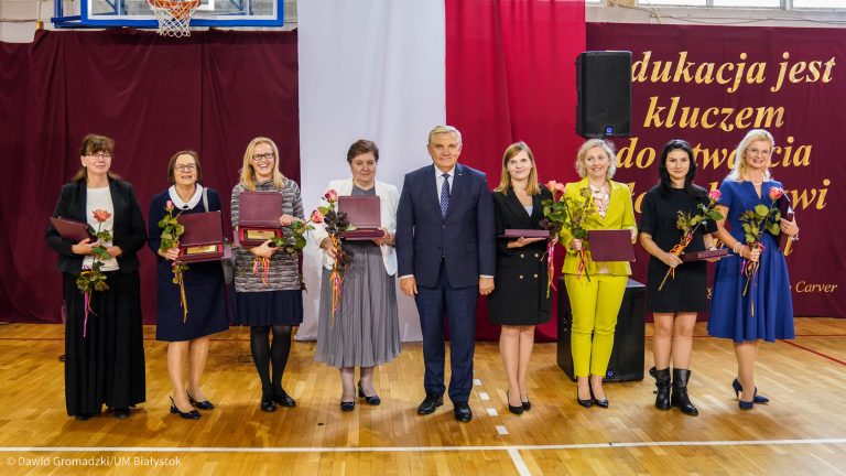 8 nagrodzonych kobiet stoi z dyplomami i kwiatami na salikobiet