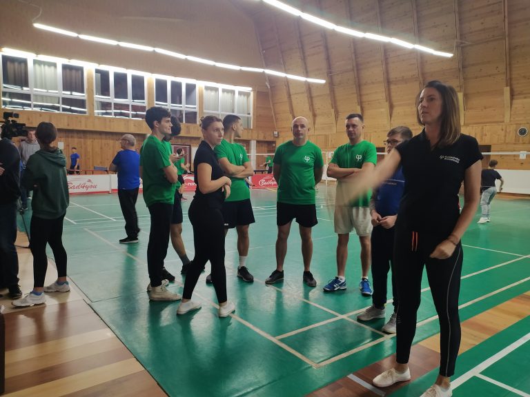 Grupa ludzi w sportowych strojach stoi na hali sportowej