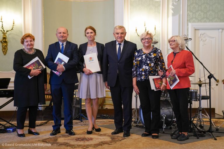 Grupa osób stoi z duplomami obok prezydenta miasta