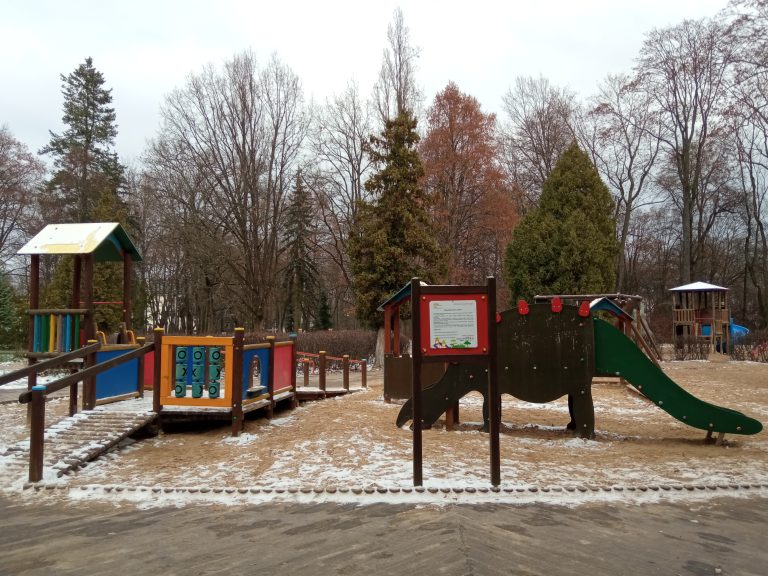 Wejscie na plac zabaw, w tle drewniane elementy konstrukcjiy