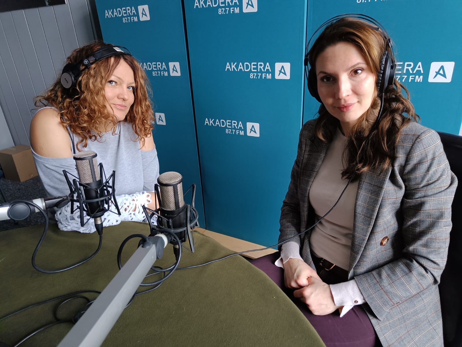 Dwie kobiety siedza w studio radiowym przed mikrofonami