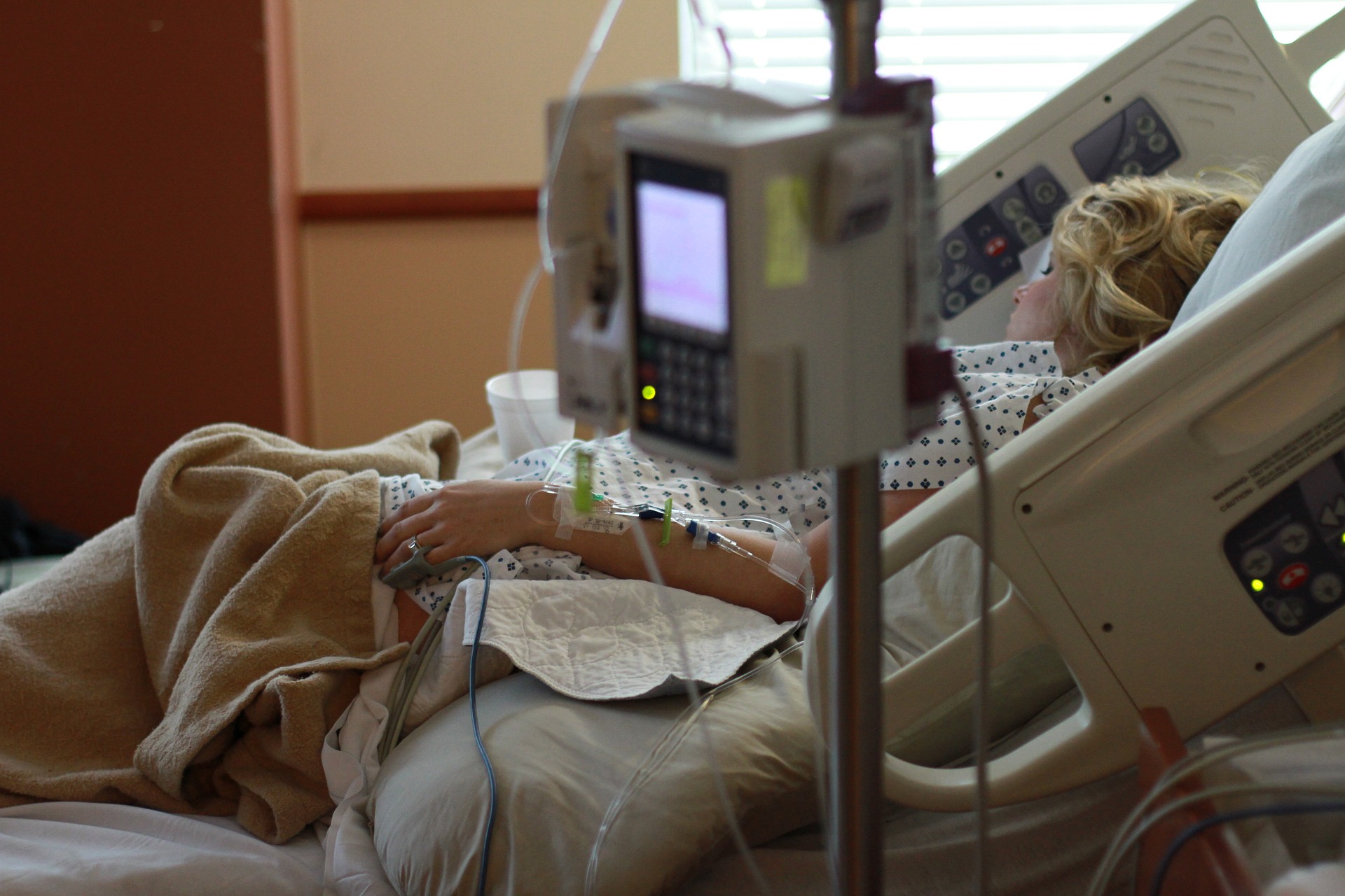 Kobieta leży na szpitalnym łóżku, obok aparatura
