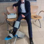 Młody mężczyzna trzyma nogę w urządzeniu do rehabilitacji stawu skokowego