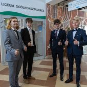 Maturzyści wznoszą kciuki na szkolnym korytarzu