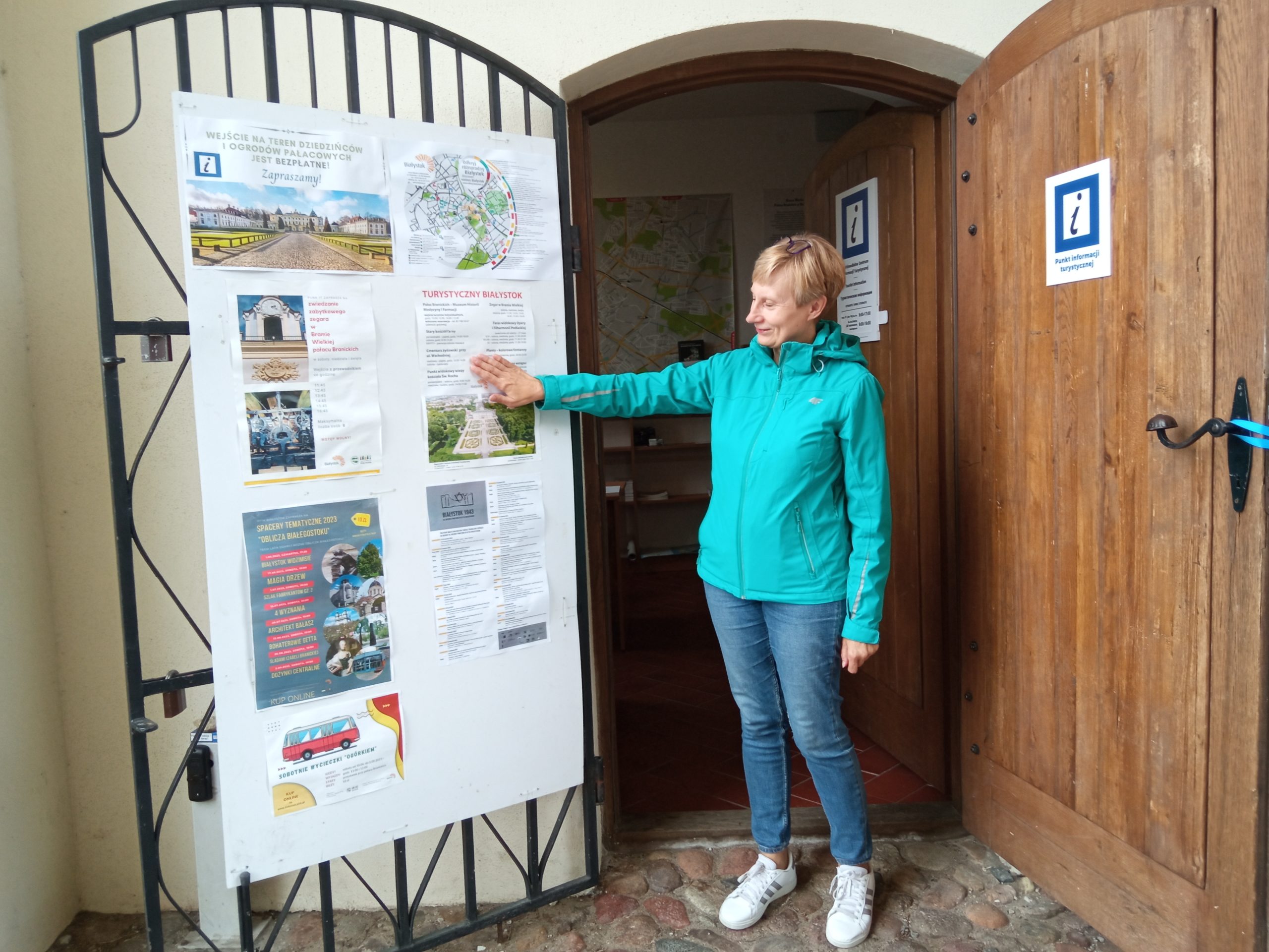 Kobieta stoi w otwartych drzwiach pr y turystycznych tablicach