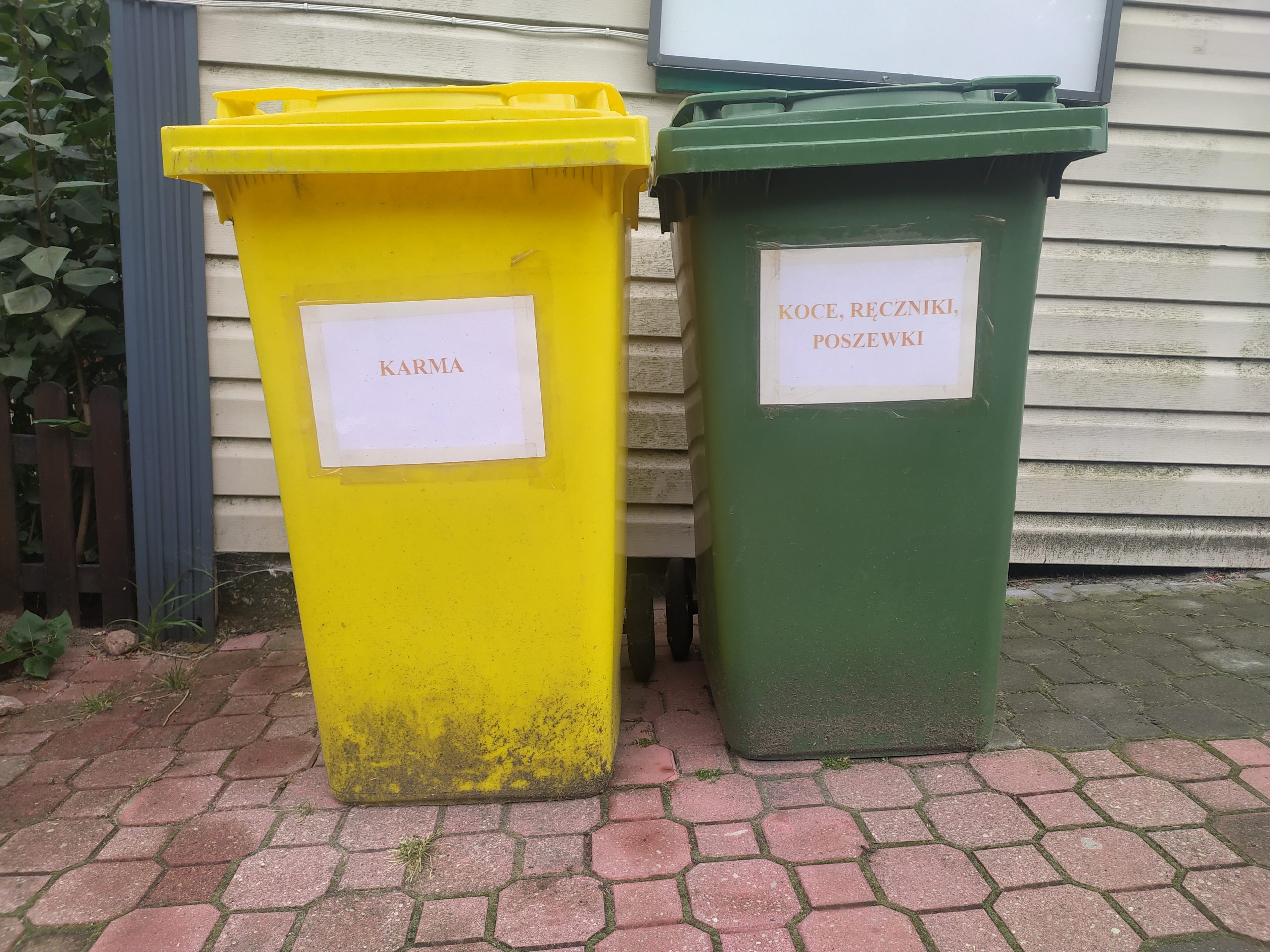 Dwa kontenery, jeden podpisany "karma", drugi podpisany poszwy "koce, ręczniki, poszwy".