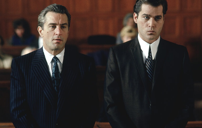Kadr z filmu "Chłopcy z ferajny". Przed sądem stoi dwóch ubranych w czarne garnitury mężczyzn.