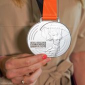 Kobieca dłoń trzyma Srebrny medal